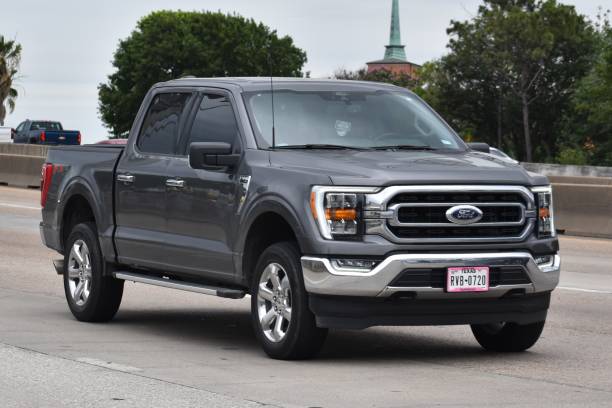 A portrait of a gray Ford F-150 pick-up truck traveling down a highway in moderate traffic Houston, TX USA - 5/11/2024 - A portrait of a gray Ford F-150 pick-up truck traveling down a highway in moderate traffic ford truck black stock pictures, royalty-free photos & images