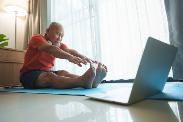 istock Elderly Asian man practicing yoga at home, following an online tutorial on a laptop 2152530254