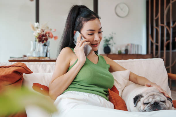 istock Engaged in call, woman sits with pug on a sunny day 2152530363