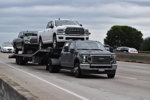 A portrait of a Ford car transport hauling Ram pick-up trucks traveling down a highway in moderate traffic Houston, TX USA - 5/11/2024 - A portrait of a Ford car transport hauling Ram pick-up trucks traveling down a highway in moderate traffic ford truck black stock pictures, royalty-free photos & images