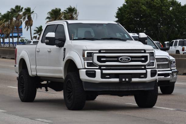 A portrait of a white Ford F-250 pick-up truck traveling down a highway in moderate traffic Houston, TX USA - 5/11/2024 - A portrait of a white Ford F-250 pick-up truck traveling down a highway in moderate traffic ford truck black stock pictures, royalty-free photos & images