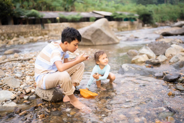 little boy and his brother playing and walking in the river