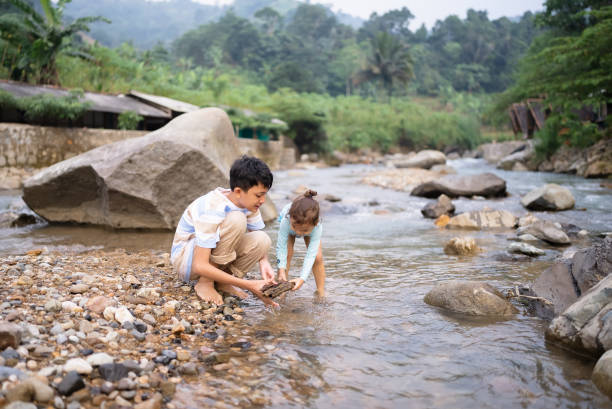 little boy and his brother playing and walking in the river