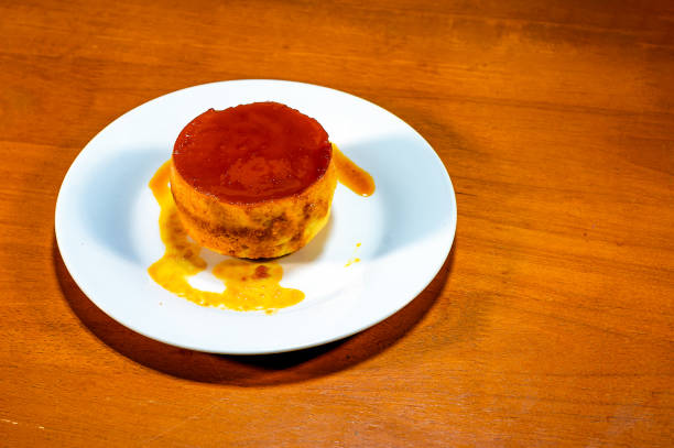 Delicious homemade custard pudding in a white plate on a wooden table, a popular menu at a coffee shop in Thailand.