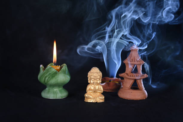 Asian incense stick in stick holder burning with smoke on dark background, close up. Meditation, yoga, self development and sound therapy concept