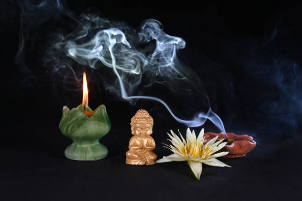 istock Buddha statue with lit candle and smoke on dark background 2152538632