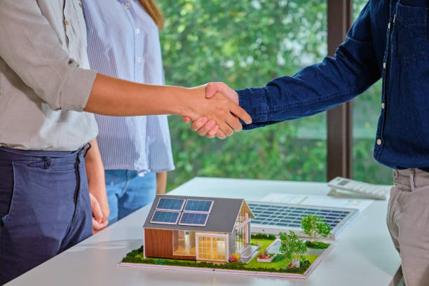 istock Close up hand couples shaking hands with Solar energy sales engineering  over a  home model  featuring solar panels successful  deal agreement  symbolizing a green energy  sustainable 2152543047