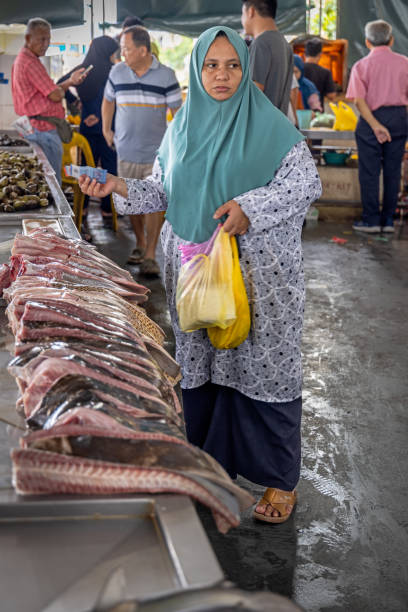 Sandakan, Eastern Borneo, Malaysia - February 19th 2024: Female customer in front of cut up meat from a ray fish at a fishmongers desk at the fish market