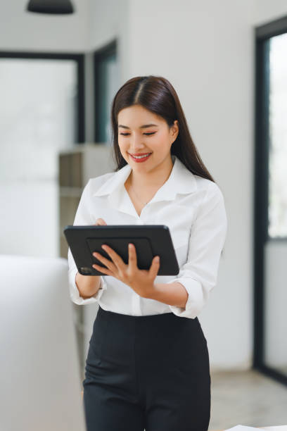 istock Smiling businesswoman in white shirt using digital tablet in modern office. 2152546751