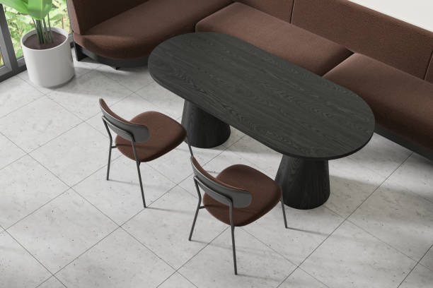 istock A modern cafe interior with a black oval table, stylish chairs, a sofa, and a plant, against a tiled floor, with light coming from the side. 3D Rendering 2152552368