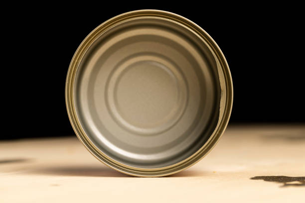 an empty aluminum can, an open round can for canning on a wooden table