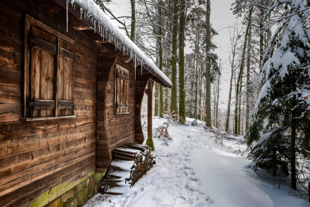A small wooden cabin surrounded by thick snow in a quiet mountain valley