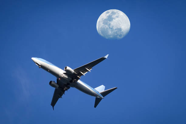 istock Airplane soaring through the moon on blue sky 2152557236