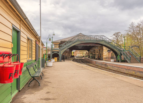 Pickering, UK. April 24, 2024.  A  themed railway station of the North Yorkshire Moors Railway at Pickering in North Yorkshire.  A hut with fire buckets are in the foreground and a bridge crosses the rails.