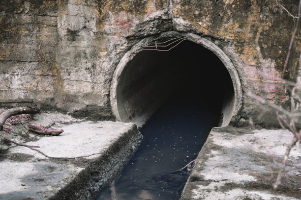 View through an arched tunnel carrying a stream beneath a bridge