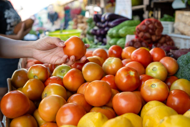 A customer choosing vegetables at an Asian farmer's stall.