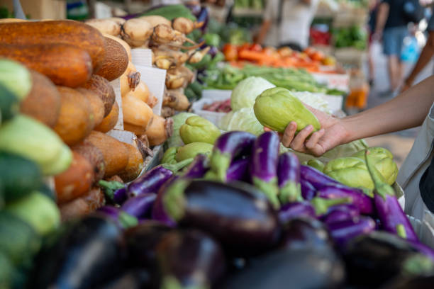 A customer choosing vegetables at an Asian farmer's stall.
