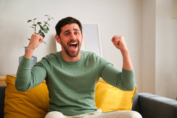 istock Happy man is sitting on a couch and is celebrating something. 2152568956