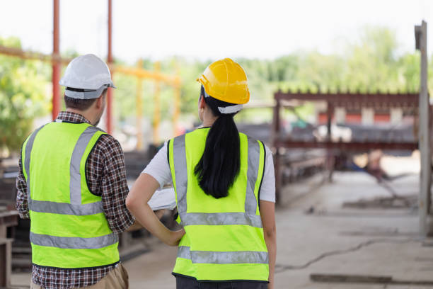 istock Back view of Engineer and female foreman worker team checking project at precast factory site, Engineer and builders in hardhats discussing on construction site 2152572481