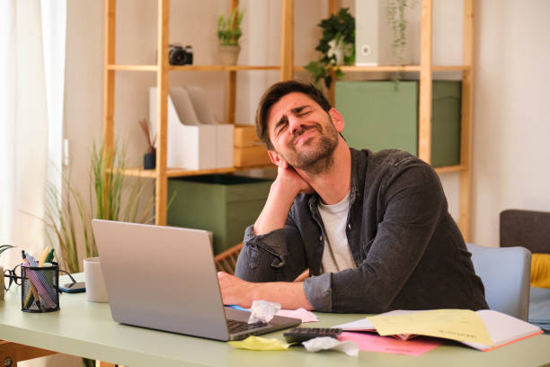 istock A man is sitting at a desk suffering neck and back pain. 2152581424