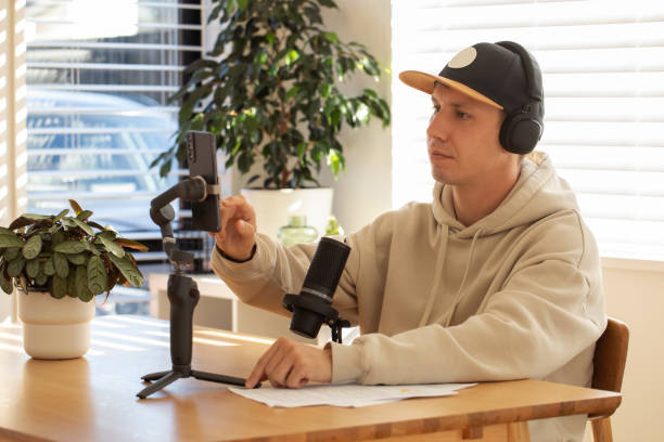 istock Man adjusts smartphone on gimbal for podcast recording in a home setup. 2152585722