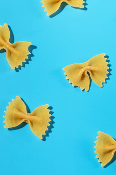 istock Uncooked bow tie pasta, farfalle scattered on a blue background in a decorative pattern 2152586126