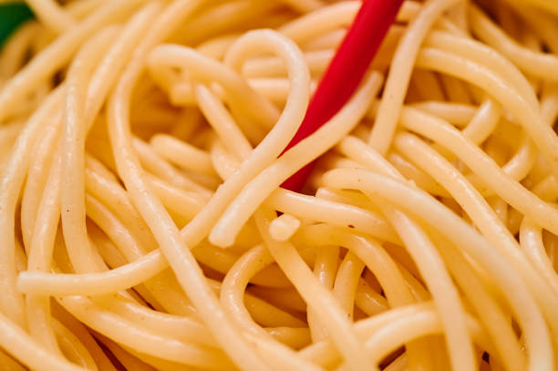 Organic semolina pasta is served in a small teal bowl with red chopsticks over a red kitchen towl