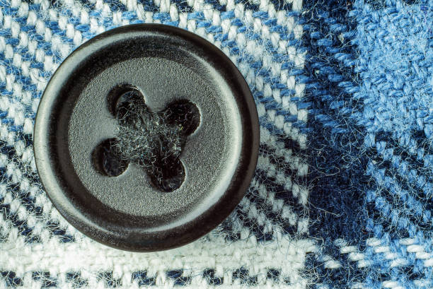 Black button on warm and soft clothing fabric close up, top view