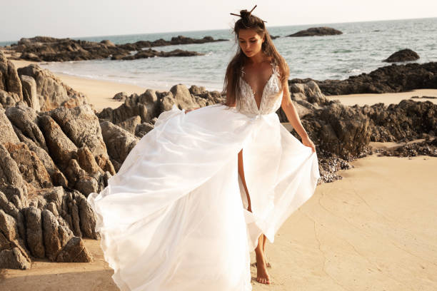 istock Beautiful bride in a flowing white dress dances on the beach 2152604005