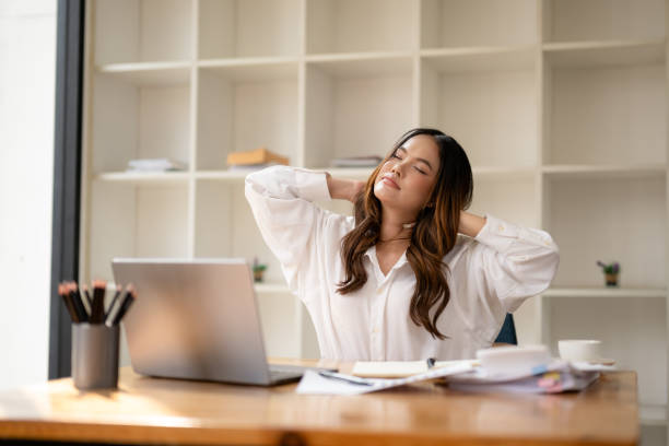 istock Young professional woman taking a stretching break at her office workspace, smiling with satisfaction. 2152611435