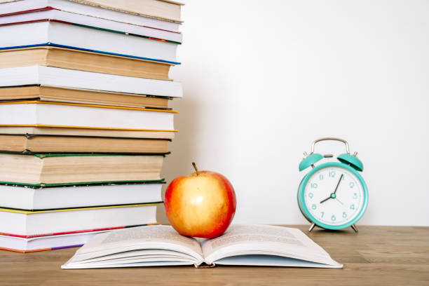 istock Books and an apple on a desk in a school or university classroom. Education, study concept background 2152613057