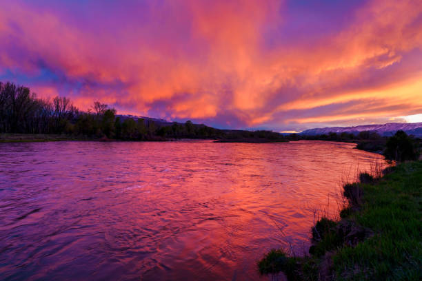 Dramatic Red and Pink Sunset with Colorado River Reflections - Scenic landscape at water's edge during incredible dramatic and vibrant sunset. Vivid red, pink and orange hues juxtaposed against cool blue tones in this nature landscape image. Colorado River, USA.