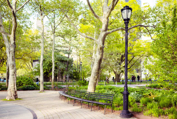 This is a photograph of the sidewalk with lampost and benches on a spring day in Battery Park, New York City, USA.