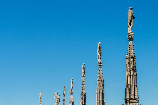 Milan, Italy - March 14, 2023: Statues on Milan Cathedral soaring into a clear blue sky, showcasing Gothic architecture