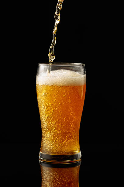 istock Pouring beer into a glass on a black reflective background. 2152620862