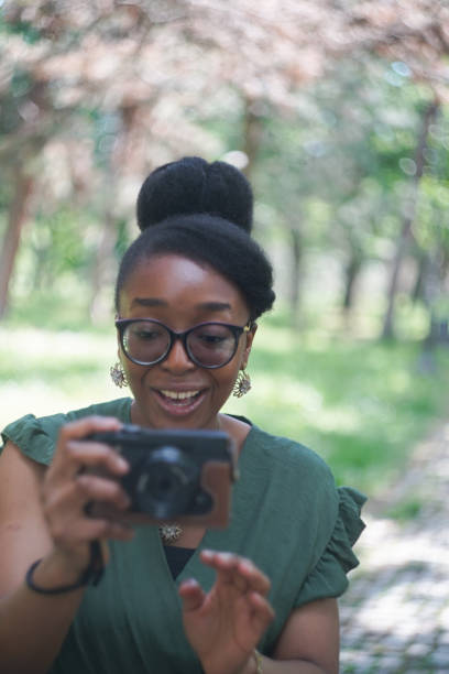 istock Young black woman taking photos with a compact camera in the park 2152620971
