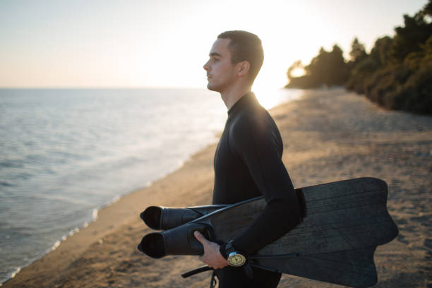 Diver holding fins and looking at water