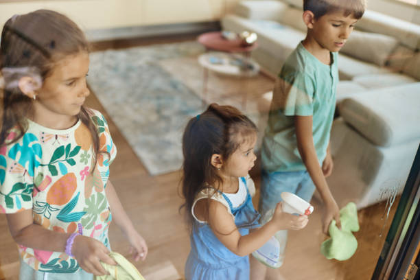 Beautiful siblings helping with chores, cleaning the window.