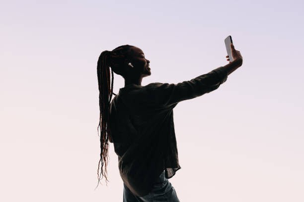 istock Confident young woman smiling and taking selfie with smartphone in studio 2152639498
