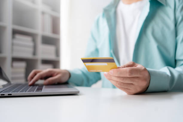 istock Man making financial transactions using credit card and laptop computer. Young man paying online, using banking service, entering information, shopping, ordering in internet store, doing secure paymen 2152639764