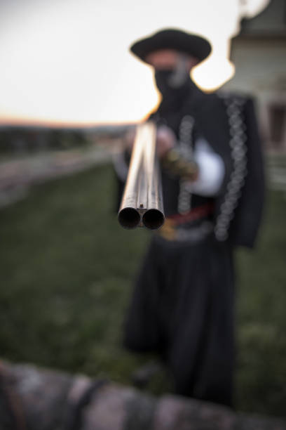 Outlaw man with shotgun pointing into camera, depth of field