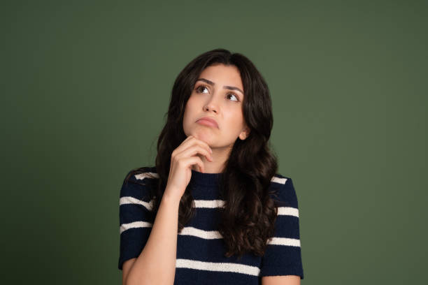 istock Young woman with a thinking face expression over green background 2152643744