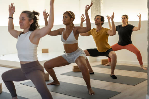 istock Fitness class in warrior pose with instructor leading in bright yoga studio. 2152646530
