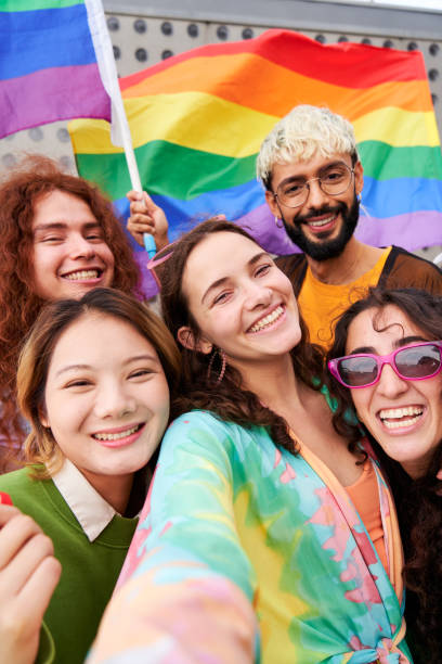 istock LGBTQIA people in pride day, taking a vertical selfie looking at camera smiling with rainbow flags. 2152648703