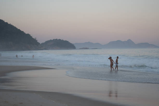 copacabana sea beach, rio de jeneiro, brazil - may 12, 2024 : people bathing on the beach with waves at sun down