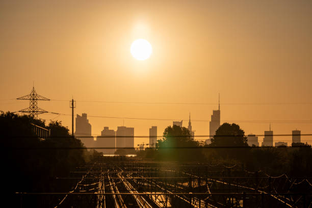 As dawn breaks, the rising sun highlights the contours of Warsaw's towering skyline alongside the city's railway.