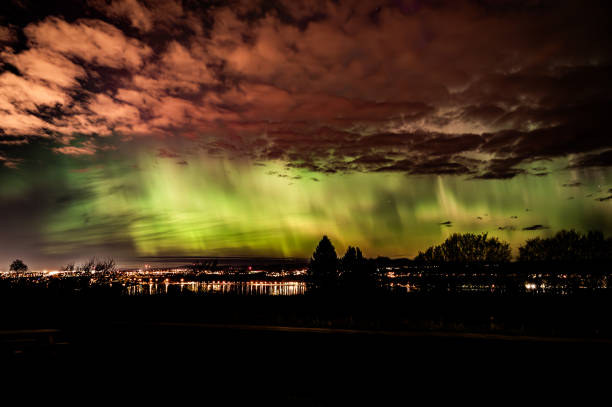 Northern Lights over a inhabited mountain with residential lights and moonlight