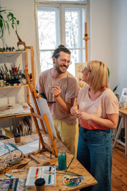 istock Smiling art partners at creative studio painting on canvas together. 2152657766