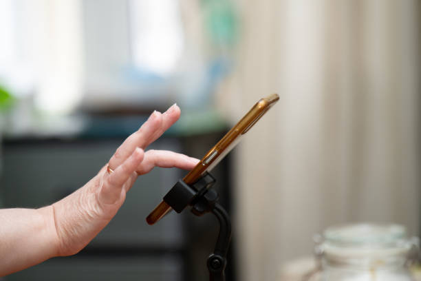 Woman's hand pressing on a smartphone screen mounted on a stand