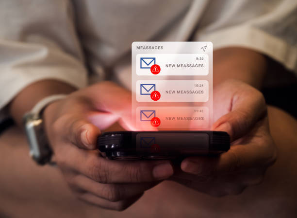 istock SMS spam and fake text message phishing concept. System hacked warning alert, email hack, scam malware spreading virus on messages alert virtual on mobile smart phone screen in hands, dark tone. 2152673067